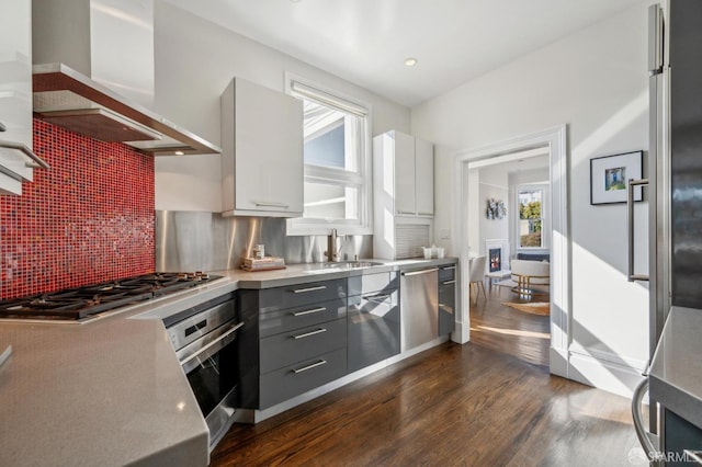 kitchen featuring appliances with stainless steel finishes, light countertops, wall chimney exhaust hood, and gray cabinetry