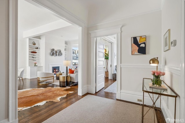 corridor featuring built in shelves, wood finished floors, and baseboards