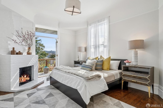 bedroom with access to outside, a fireplace, and wood finished floors