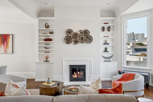 living area featuring a fireplace, built in shelves, and dark wood-style floors