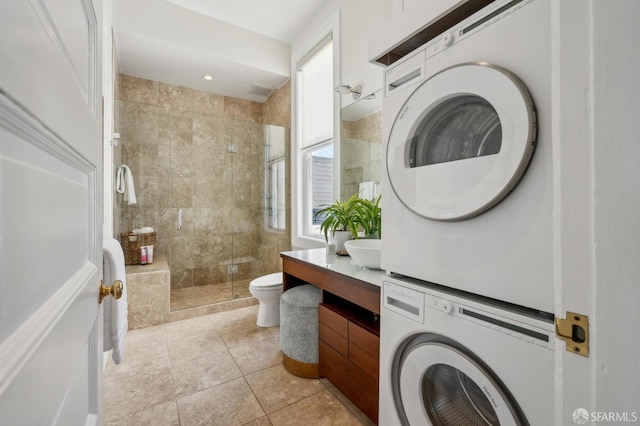 bathroom featuring a shower stall, toilet, tile patterned floors, vanity, and stacked washer / drying machine