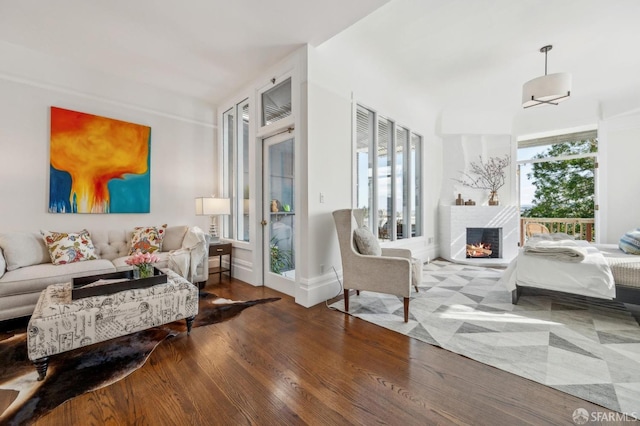 living room with a warm lit fireplace and wood finished floors