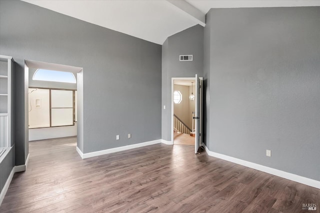 spare room with dark hardwood / wood-style flooring and lofted ceiling with beams