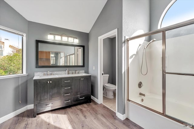 full bathroom with vaulted ceiling, toilet, wood-type flooring, bath / shower combo with glass door, and vanity