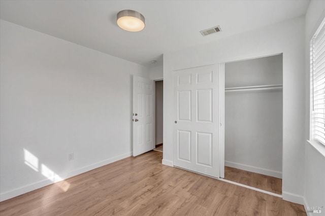 unfurnished bedroom with a closet, light hardwood / wood-style flooring, and multiple windows