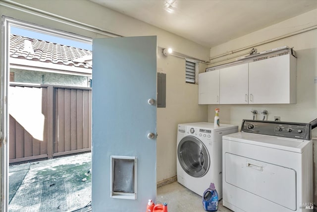 clothes washing area with washer and clothes dryer, electric panel, and cabinets