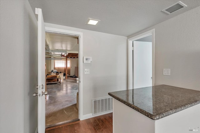 hallway with a textured ceiling and dark hardwood / wood-style flooring