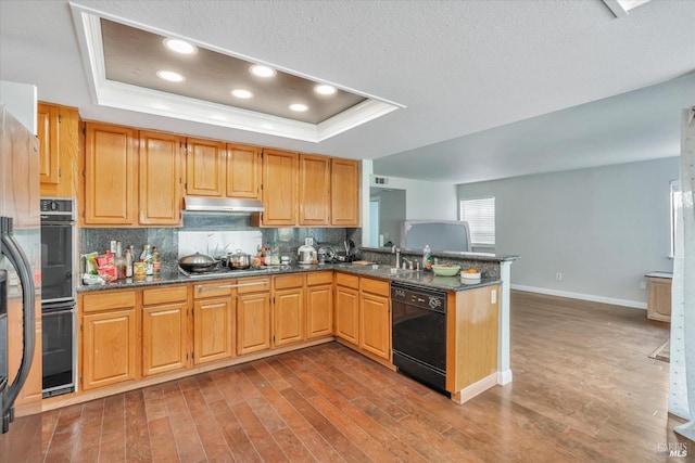 kitchen with sink, gas cooktop, black dishwasher, a raised ceiling, and kitchen peninsula