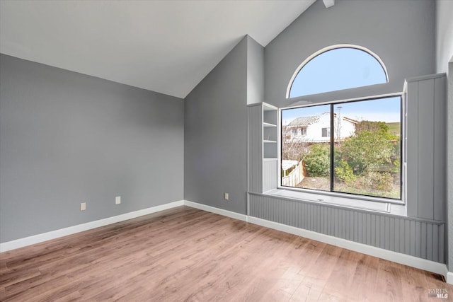 additional living space with lofted ceiling with beams, built in shelves, and light wood-type flooring