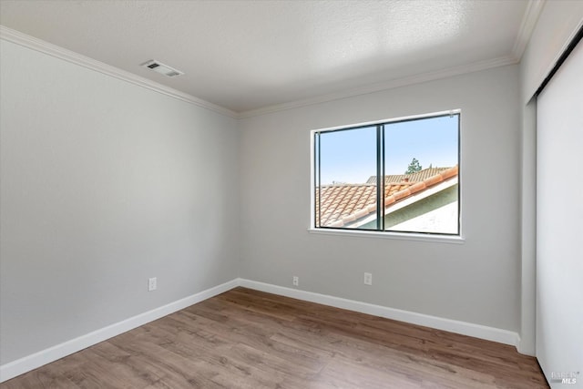 unfurnished room with ornamental molding, light wood-type flooring, and a textured ceiling