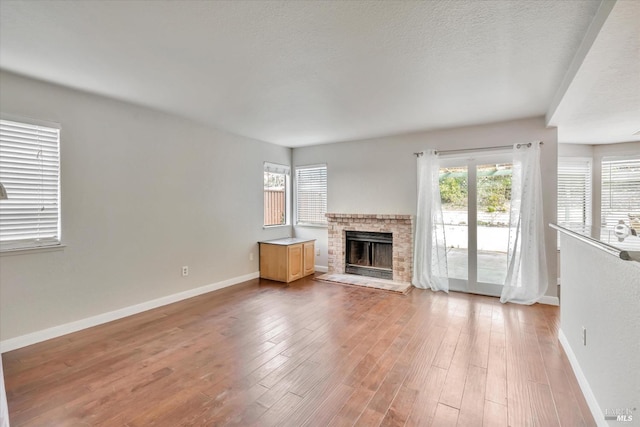 unfurnished living room featuring a brick fireplace, a textured ceiling, and hardwood / wood-style flooring