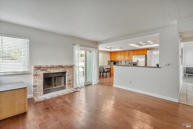 unfurnished living room with light hardwood / wood-style flooring, a brick fireplace, and a raised ceiling