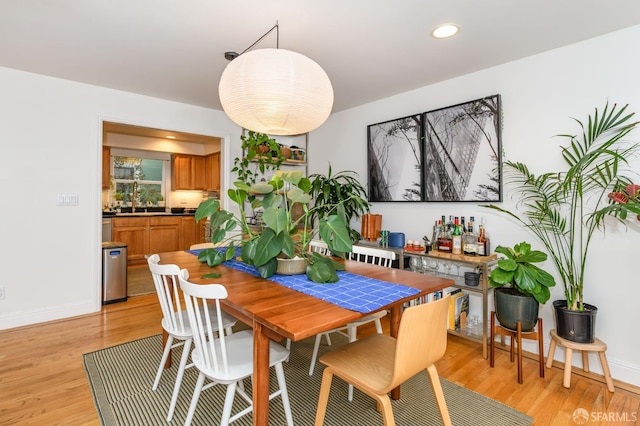 dining area with light hardwood / wood-style flooring and wet bar