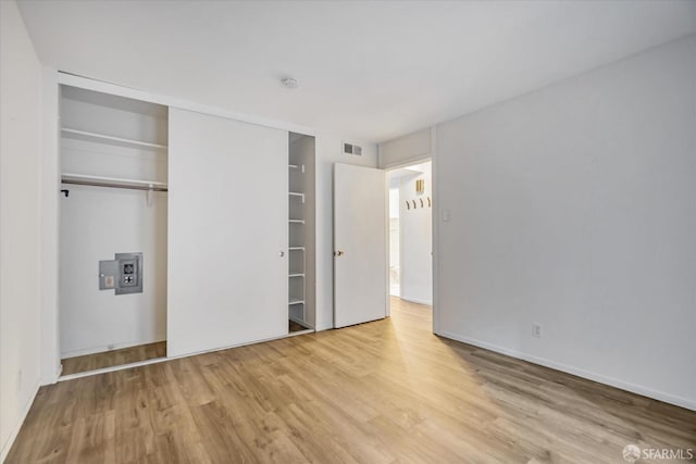 unfurnished bedroom featuring a closet, electric panel, and light hardwood / wood-style floors