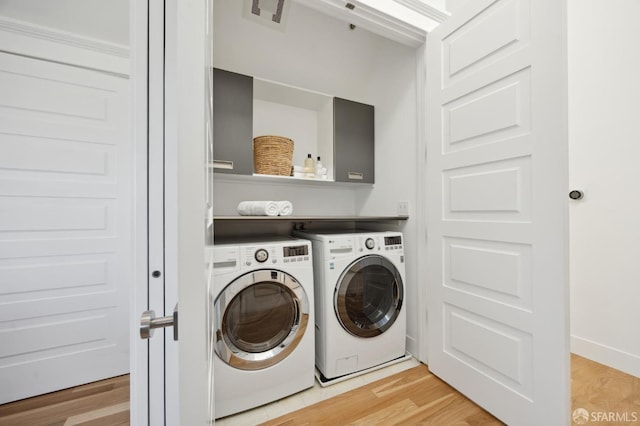 laundry room with washing machine and clothes dryer and light hardwood / wood-style floors