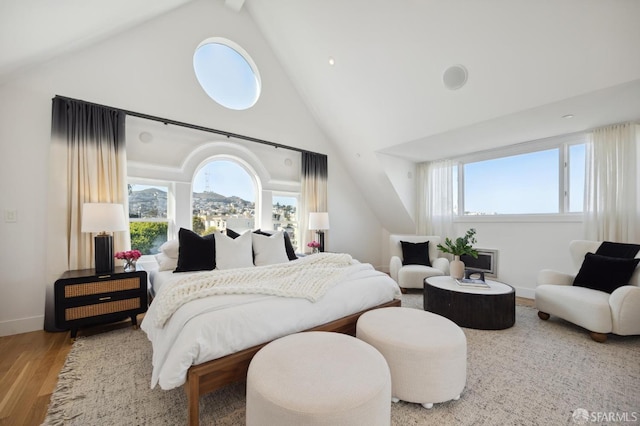 bedroom with vaulted ceiling with beams and wood-type flooring