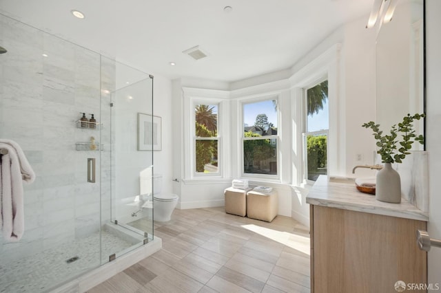 bathroom featuring toilet, tile patterned floors, a shower with shower door, and vanity