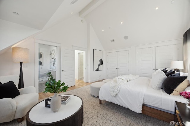 bedroom with multiple closets, beam ceiling, light hardwood / wood-style flooring, and high vaulted ceiling