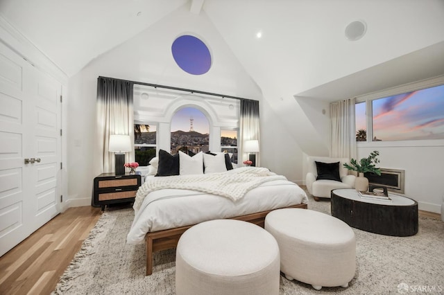 bedroom featuring lofted ceiling with beams and light hardwood / wood-style floors