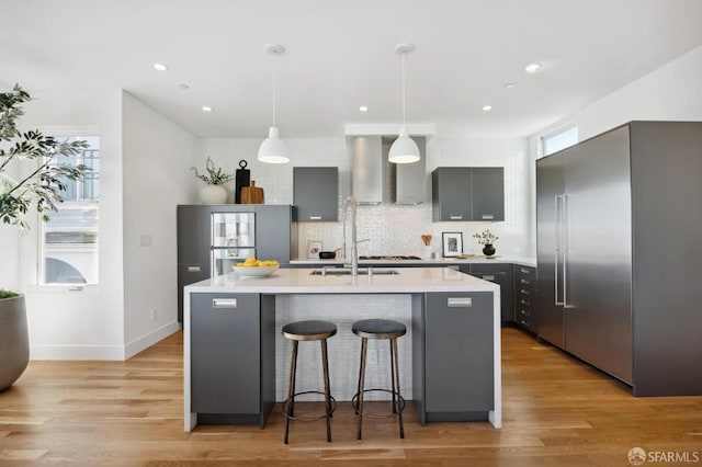 kitchen with decorative light fixtures, stainless steel built in refrigerator, gray cabinetry, and a healthy amount of sunlight