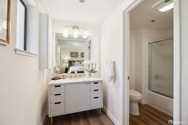 full bathroom featuring toilet, combined bath / shower with glass door, hardwood / wood-style flooring, and vanity