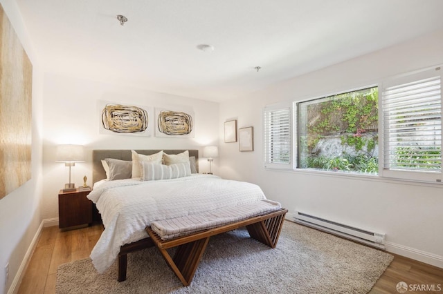 bedroom with a baseboard heating unit and hardwood / wood-style flooring