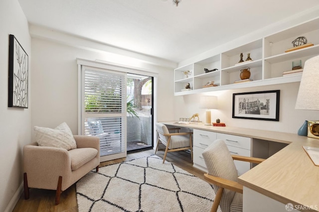 office space with built in desk and light hardwood / wood-style floors