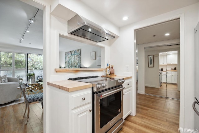 kitchen featuring extractor fan, wood counters, white cabinetry, light hardwood / wood-style floors, and stainless steel range with electric stovetop