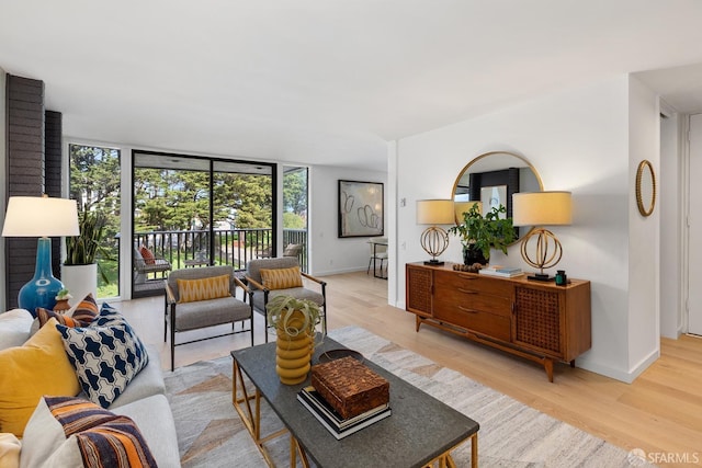 living area featuring a wall of windows, baseboards, and light wood-style flooring
