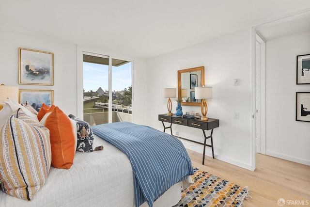 bedroom featuring wood finished floors, baseboards, and access to exterior