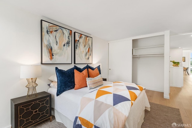 bedroom with wood finished floors, a closet, and baseboards