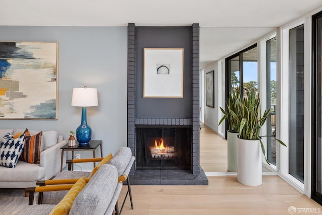 living area featuring light wood-style floors, a fireplace, baseboards, and floor to ceiling windows