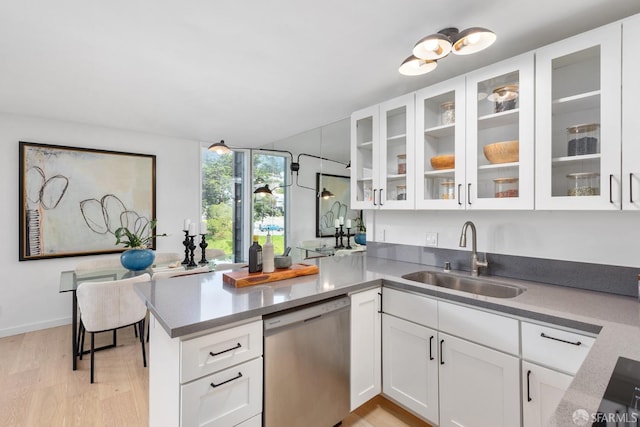 kitchen with dishwasher, a sink, a peninsula, light wood-style floors, and white cabinetry