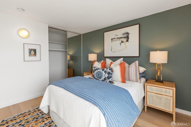 bedroom with wood finished floors, baseboards, and a closet