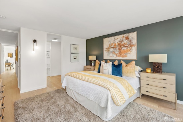 bedroom featuring light wood finished floors and baseboards