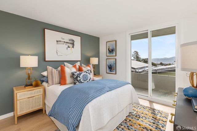 bedroom featuring access to outside, light wood finished floors, and baseboards