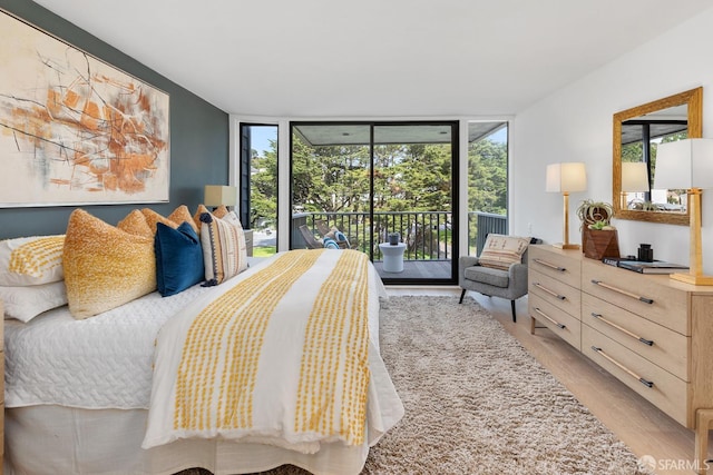bedroom with floor to ceiling windows, access to outside, light wood finished floors, and multiple windows