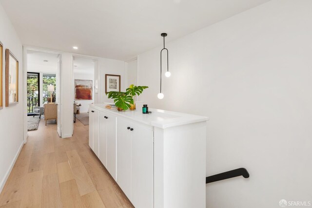 hallway with light wood-style floors, recessed lighting, and an upstairs landing