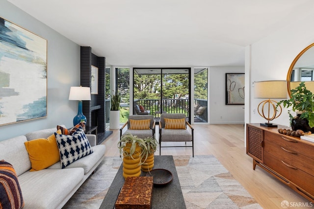 living room featuring light wood-style floors, floor to ceiling windows, and baseboards