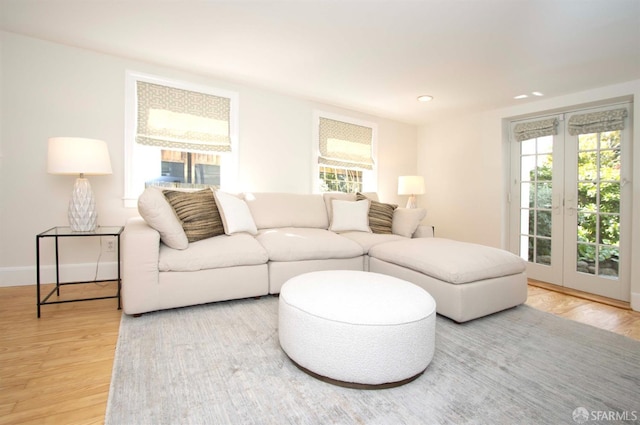 living room with a healthy amount of sunlight, french doors, and light wood-style floors