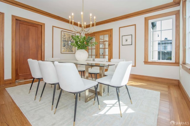 dining area featuring crown molding, a notable chandelier, baseboards, and light wood finished floors