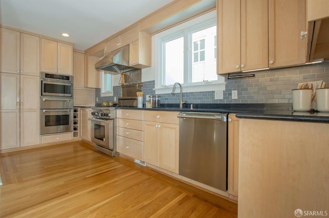 kitchen with under cabinet range hood, stainless steel appliances, light brown cabinetry, and a sink