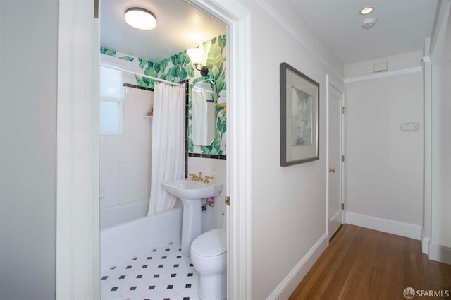 bathroom with toilet, shower / bath combo, and baseboards