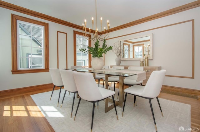 dining room with a chandelier, crown molding, baseboards, and wood finished floors