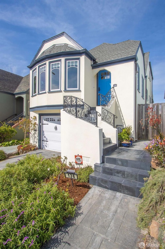 view of front of property featuring stucco siding, a garage, stairs, and a shingled roof