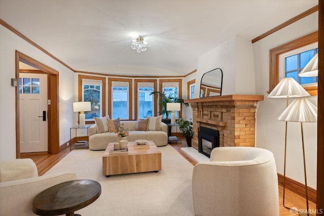 living area with plenty of natural light, ornamental molding, a fireplace, and wood finished floors