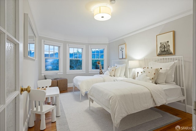 bedroom featuring wood finished floors, baseboards, and ornamental molding