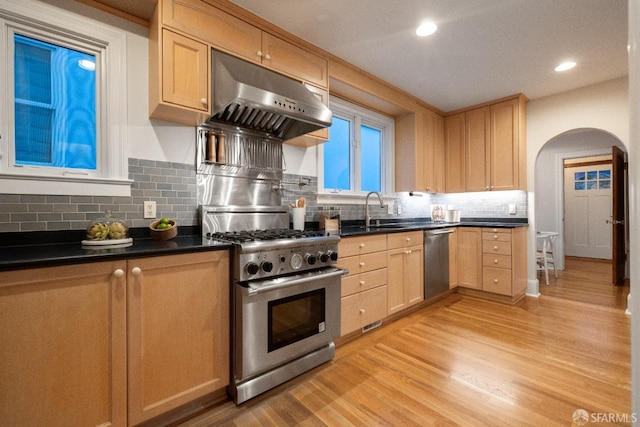 kitchen featuring light brown cabinets, arched walkways, a sink, stainless steel appliances, and under cabinet range hood