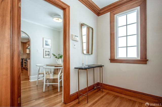 corridor with crown molding, wood finished floors, arched walkways, and baseboards