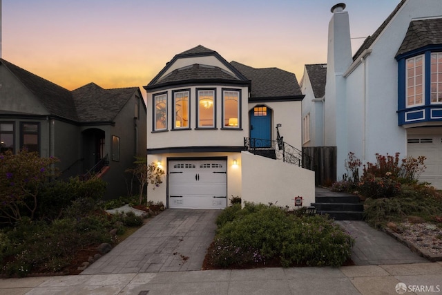 view of front facade with concrete driveway, an attached garage, and stucco siding